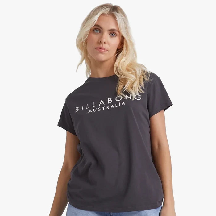 Blonde woman wearing an off-black Billabong Serenity short sleeve tee, presented in a casual, studio shot.