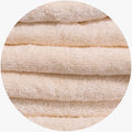 Close-up of fluffy beige Colibri Imperial Zerotwist bath sheets stacked horizontally, showcasing the soft terrycloth texture.