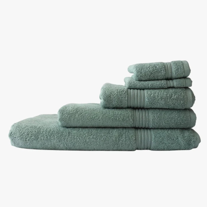 Stack of soft green Colibri Imperial Zerotwist bath towels, folded neatly in various sizes, on a plain background.