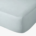 Duck egg blue Cotton Co 400 thread count queen fitted sheet on a mattress, shown in a close-up angled view.