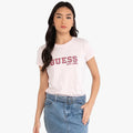 Front view of a woman wearing a pink Guess College short sleeve tee with the Guess logo, paired with a blue denim skirt.