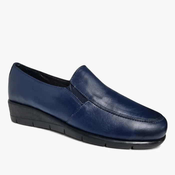 A single navy blue Hush Puppies Womens Grecia slip-on wedge shoe, made of smooth leather, displayed against a light