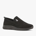 Hush Puppies Womens Rimba Slip On Sneaker in black, featuring a knit upper and rubber sole, shown from a side view.