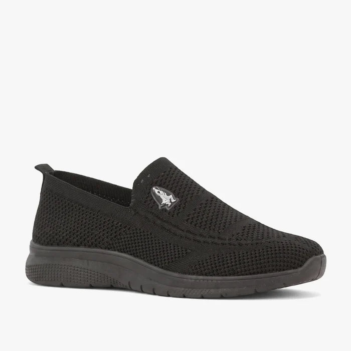 Hush Puppies Womens Rimba Slip On Sneaker in black, featuring a knit upper and rubber sole, shown from a side view.